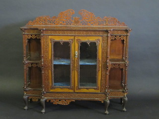 A Victorian mahogany cabinet with pierced raised back, the  centre section fitted a cupboard enclosed by glazed panelled  doors flanked by a pair of niches with blind fret work decoration  throughout, raised on cabriole supports 48"