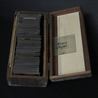 A rectangular wooden box with hinged lid containing a collection of magic lantern slides