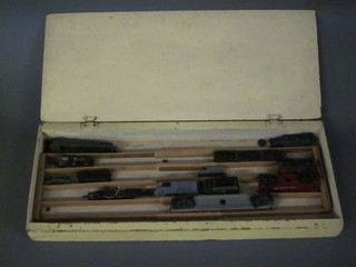 A shallow rectangular wooden box containing a small collection  of various rolling stock, trains etc