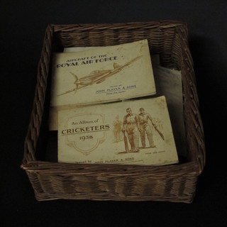 A wicker basket containing a collection of various cigarette card  albums