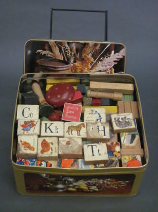 A collection of painted wooden blocks contained in a metal  biscuit tin