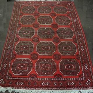 A machine made red ground Eastern style carpet with 15  octagons to the centre, slight hole, 105" x 75"