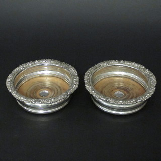A pair of circular silver plated bottle coasters with cast borders