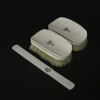 A pair of ivory backed military hair brushes with armorial decoration and an ivory newspaper opener