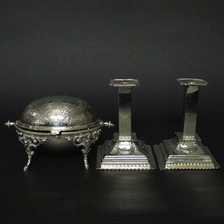 An oval engraved silver plated roll topped butter dish and a pair of square silver plated reeded candlesticks on square bases