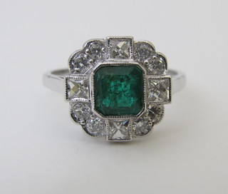 An 18ct white gold dress ring set a square emerald surrounded by diamonds