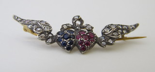 A gold brooch in the form of 2 hearts with wings, set sapphire, ruby and diamond