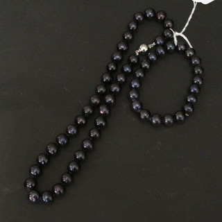 A black pearl necklace together with matching bracelet