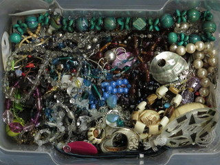 A clear plastic crate containing a collection of costume jewellery