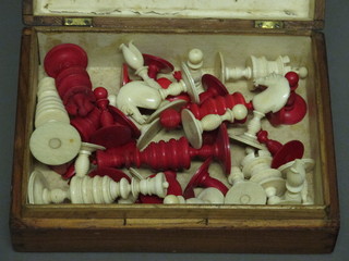 A white and red carved ivory chess set contained in a pine box with hinged lid