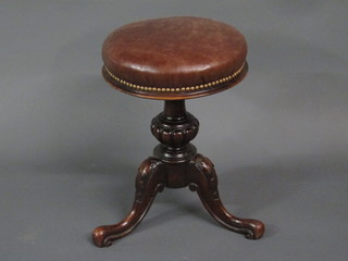 A Victorian carved walnut revolving adjustable piano stool, raised on a turned and carved pillar and tripod base