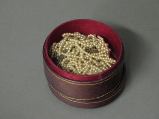 A circular leather box containing seed pearls