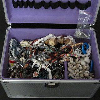 A metal case containing a collection of costume jewellery