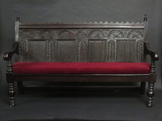 A carved oak settle, the back of panelled construction, 77"