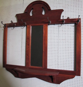 An Edwardian arched hanging coat rack, the centre fitted a bevelled plate mirror 43"