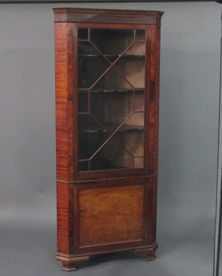 A Georgian style mahogany double corner cabinet with moulded and dentil cornice, the interior fitted shelves enclosed by astragal  glazed panelled doors, the base fitted a cupboard enclosed by a  panelled door, raised on ogee bracket feet 35"