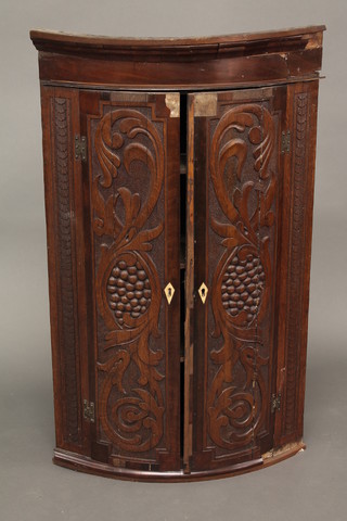 A Georgian mahogany bow front corner cabinet with moulded  cornice, fitted shelves enclosed by carved panelled doors 24"