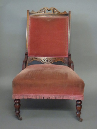 An Edwardian walnut nursing chair with upholstered seat and back, raised on turned supports