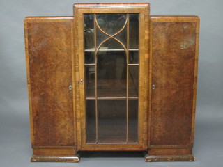 An Art Deco walnut display cabinet, the centre section fitted shelves enclosed by astragal glazed panelled doors flanked by a  pair of cupboards enclosed by panelled doors 48"
