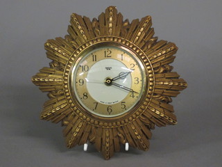 A Smiths electric wall clock with gilt chapter ring and Arabic numerals contained in a plaster sunburst case 8"