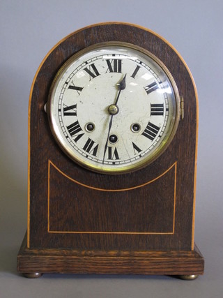 A chiming bracket clock with silvered dial and Arabic numerals contained in an oak arch shaped case