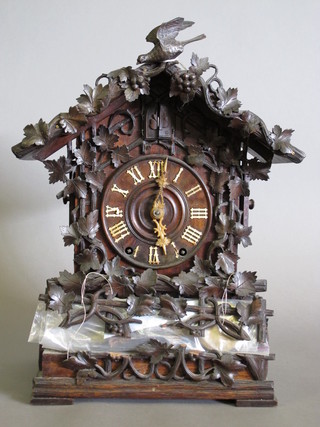 A striking cuckoo mantel clock contained in a heavily carved  wooden case 11"