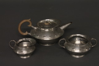 A circular planished pewter 3 piece tea set comprising teapot,  twin handled sugar bowl and milk jug