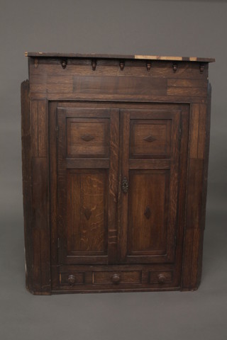 A Georgian oak hanging corner cabinet, the interior fitted shelves with moulded cornice, enclosed by a panelled door 35"