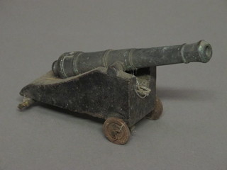 A bronze model cannon with 6 1/2" barrel, raised on a wooden trunion