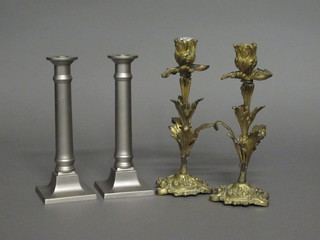 A pair of Rococo style gilt metal candlesticks 10" and a pair of  white metal candlesticks with Doric capitals 9"