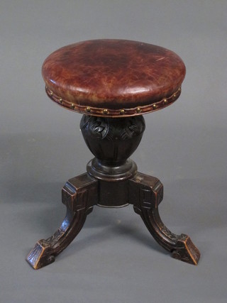 A Victorian carved walnut piano stool, the seat upholstered in leather, raised on a carved base