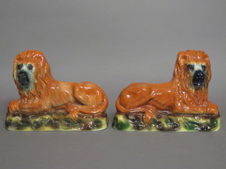 A pair of Staffordshire figures of reclining lions with glass eyes, 12", 1 with firing crack to base,