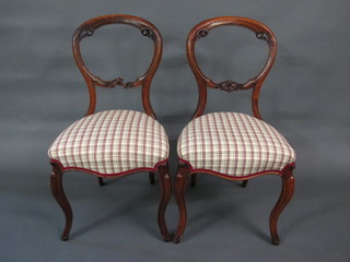 A set of 4 Victorian mahogany balloon back dining chairs with carved mid rails, the seats of serpentine outline, raised on  cabriole supports