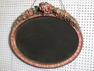 An oval bevelled plate wall mirror contained in a barbola  mounted frame 22 1/2"