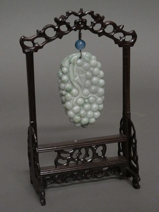 A carved green hardstone bunch of grapes, on a hardwood stand