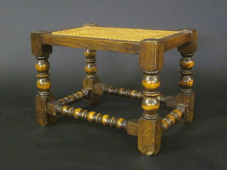 A rectangular oak stool with woven cane seat, raised on turned  and block supports 17"