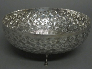 A circular embossed white metal bowl, raised on 3 scroll  supports