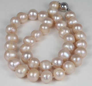 A rope of peach coloured pearls with silver clasp