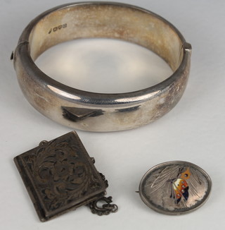 An engraved silver bracelet, a silver locket in the form of a book  hung on a silver chain together with a brooch