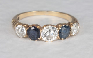 A gold dress ring set 3 diamonds surrounded by sapphires