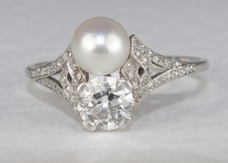 A platinum dress ring set a diamond and pearl and diamonds to  the shoulders