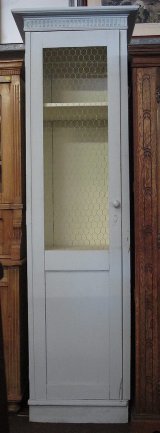 A Victorian white painted cabinet with moulded cornice, fitted shelves enclosed by a grilled panelled door, 25"