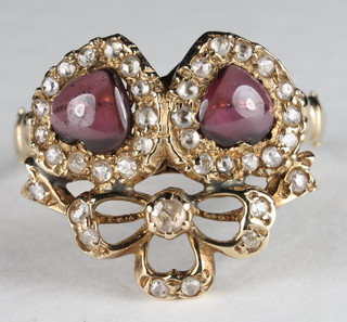A gold dress ring in the form of entwined hearts set cabouchon  cut garnets supported by diamonds