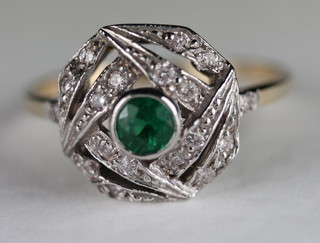 An 18ct yellow gold dress ring set a circular cut emerald surrounded by diamonds