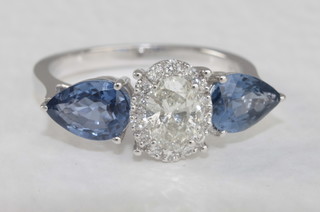 An 18ct white gold dress ring set an oval cut diamond, approx  0.61ct and set sapphires to the shoulders approx. 1.83ct