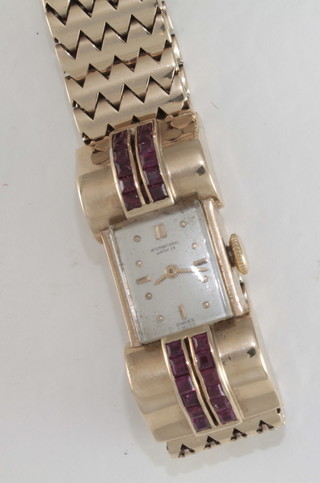 A lady's National Watch Company wristwatch contained in a 9ct  gold case with integral bracelet, the shoulders set red stones