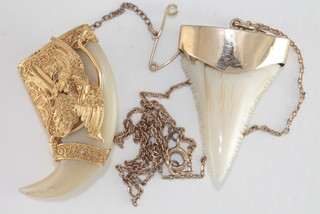 A tigers claw pendant in a gold mount hung on a fine gold chain together with a tigers claw brooch
