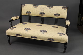 A Victorian ebonised 2 seat settee upholstered in floral material  and raised on turned supports 51"