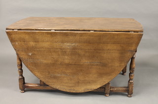 An oak oval drop flap gateleg dining table raised on turned and block supports 54"