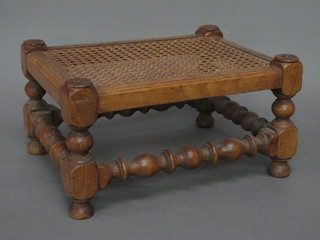 A rectangular honey oak footstool with woven rush seat raised on turned and block supports 16"